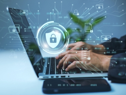 A businessman works on his laptop at home with a virtual display showing a symbol to signify cyber security privacy and online data protection